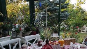 An outdoor dining area with a checkered tablecloth, baskets of bread, and various table settings including cups and plates. - Le Frêne Fringant (Sainte-Opportune-la-Mare)