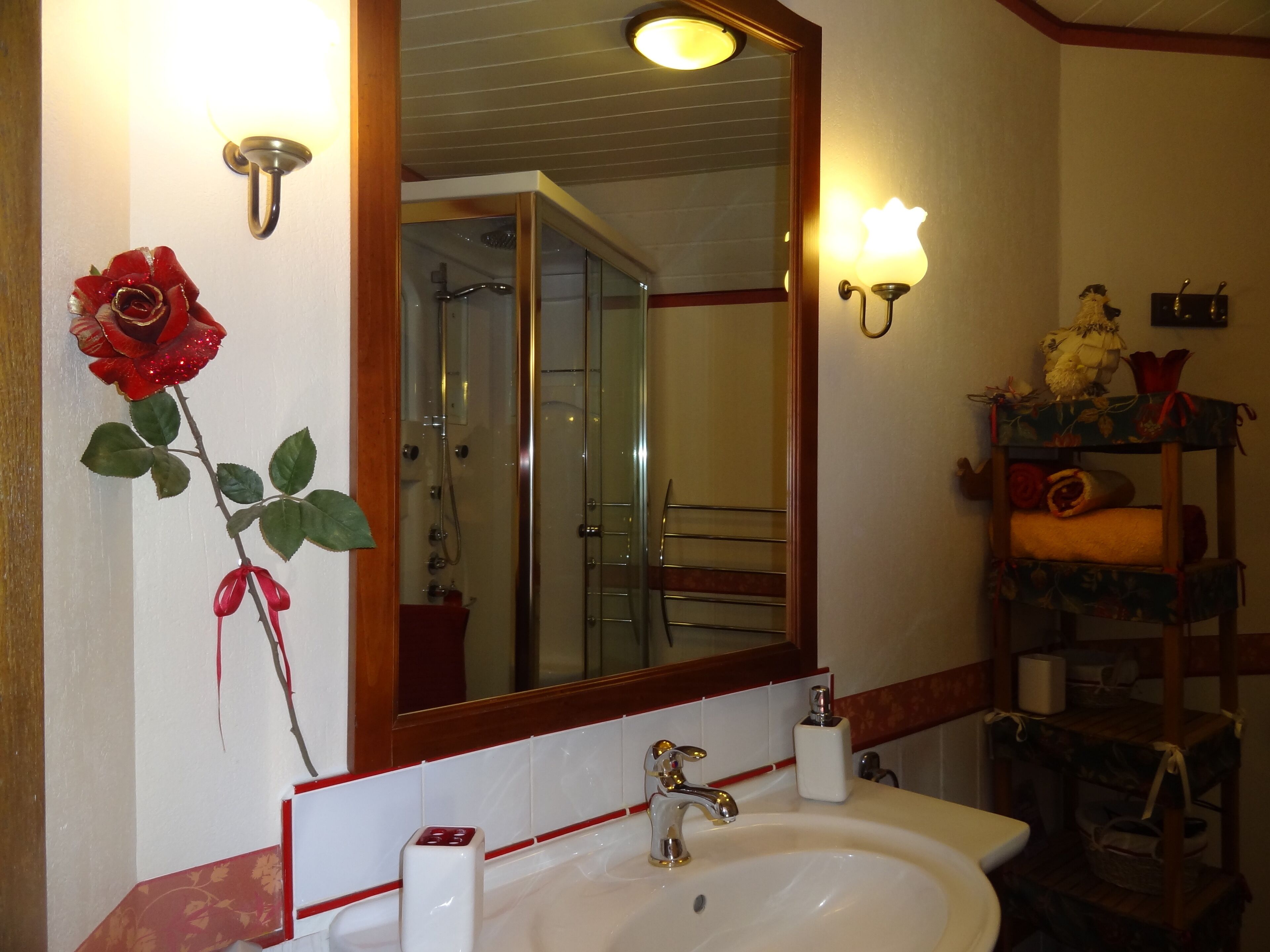 A bathroom with a white sink, a mirror, a shower, and a towel rack.