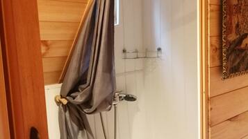 A wooden-paneled bathroom with a shower, a towel rack, and a small sink.