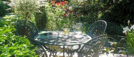 Une table ronde en métal, entourée de chaises, dans un jardin.