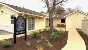 A yellow building with a sign reading "The Rellik House" and an entrance arrow. - Raven Suite at Rellik House. Winery & Alpaca Farm (Central Point)
