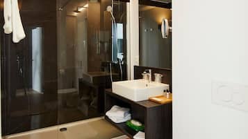 A modern bathroom with a glass-enclosed shower, a white sink, and a toilet.