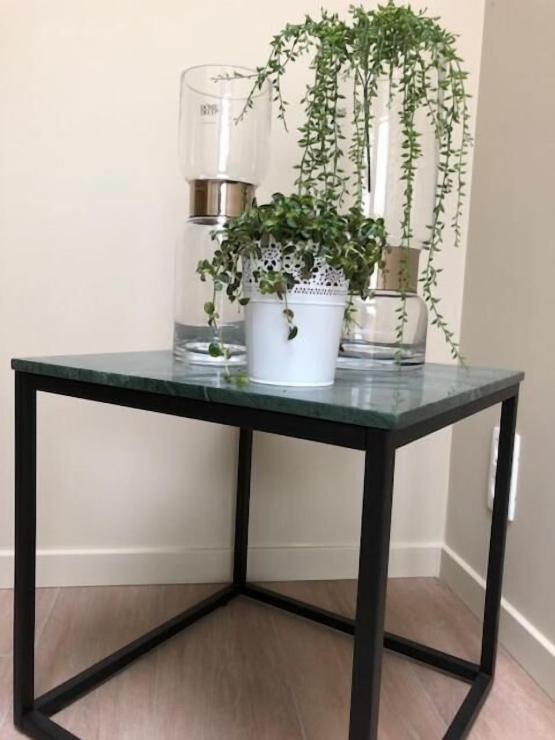 A glass-top table with a white pot containing a hanging plant.