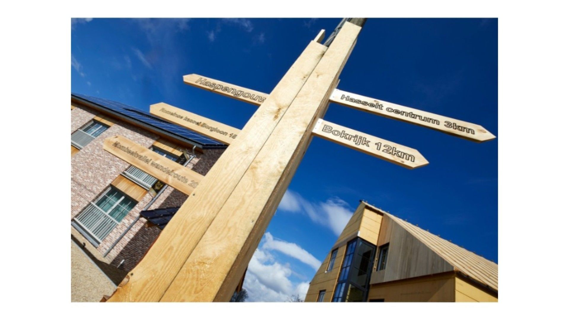 A wooden signpost with directional signs pointing to various destinations, including a hospital, a 3km distance, and a 12km distance.