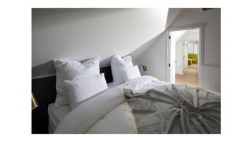 Um quarto com cama, travesseiros e mesa de cabeceira.