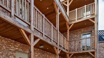 Una estructura de madera de varios niveles con balcones, paredes de ladrillo y piso de baldosas.