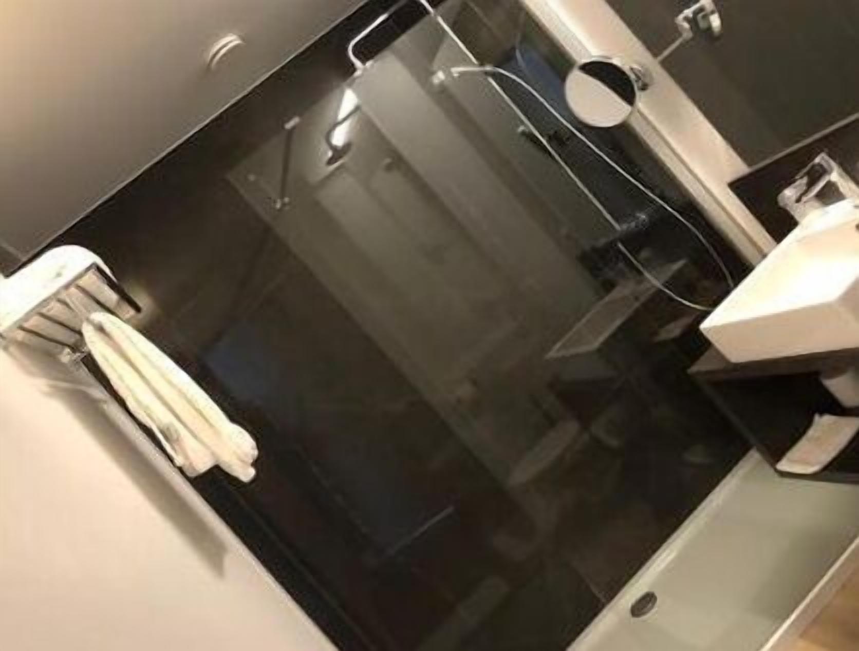 A modern bathroom with a glass shower enclosure, a white sink, and a towel rack.