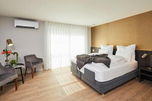 A modern hotel room with a bed, a desk, a chair, and a window with sheer curtains. - B&B Sasput (Hasselt)
