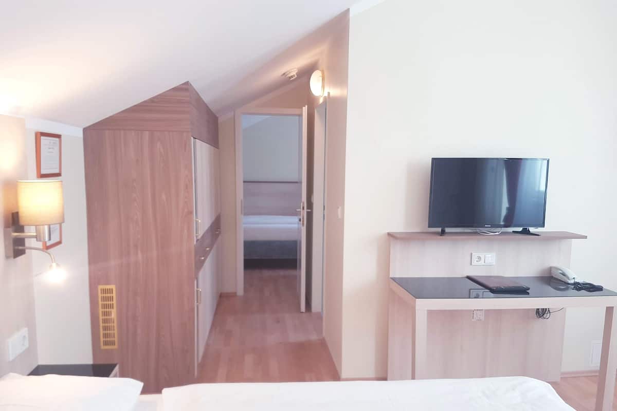 Une chambre d’hôtel avec un lit, un bureau, une télévision, un téléphone et une lampe.