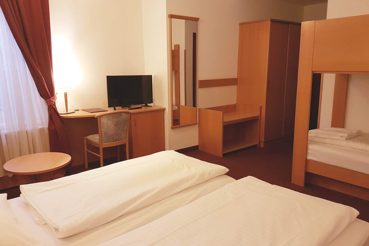 Une chambre d’hôtel avec deux lits, un bureau avec une télévision, une chaise et un miroir.