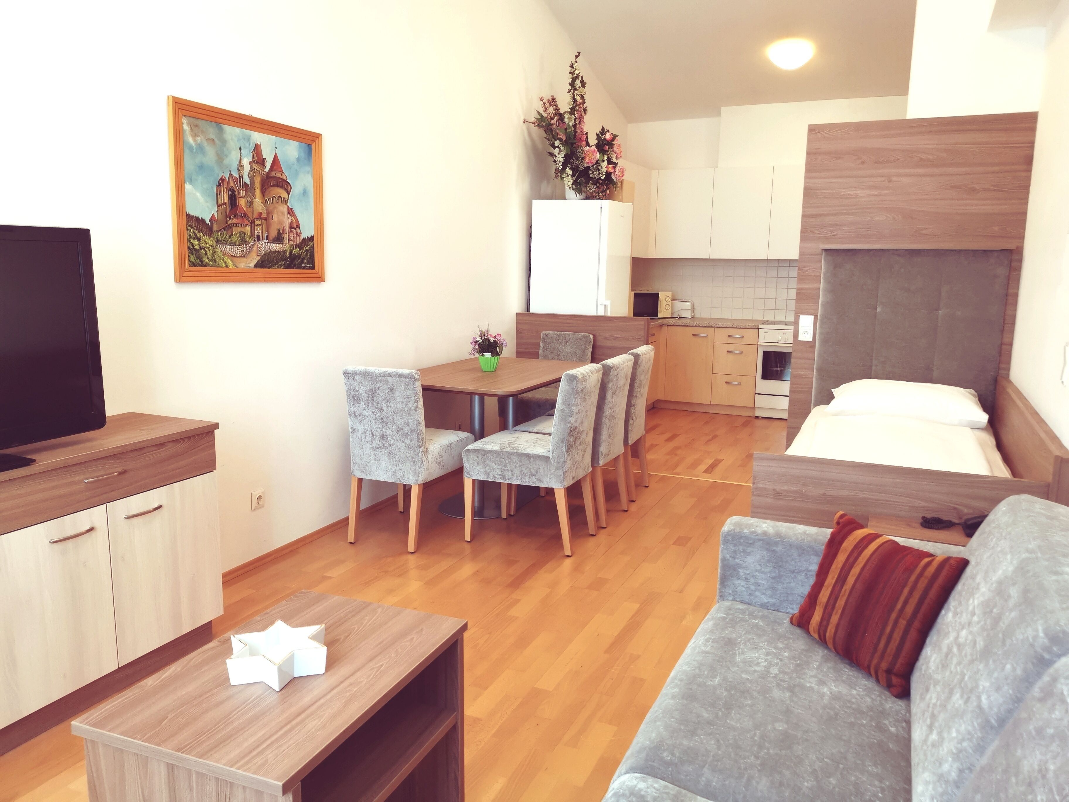 Un apartamento moderno con comedor, kitchenette y sala de estar con sofá y televisor.