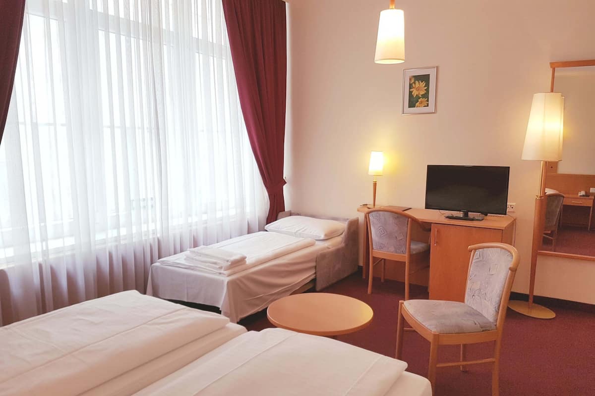 Une chambre d’hôtel avec deux lits, un bureau avec une télévision, une chaise et une petite table.