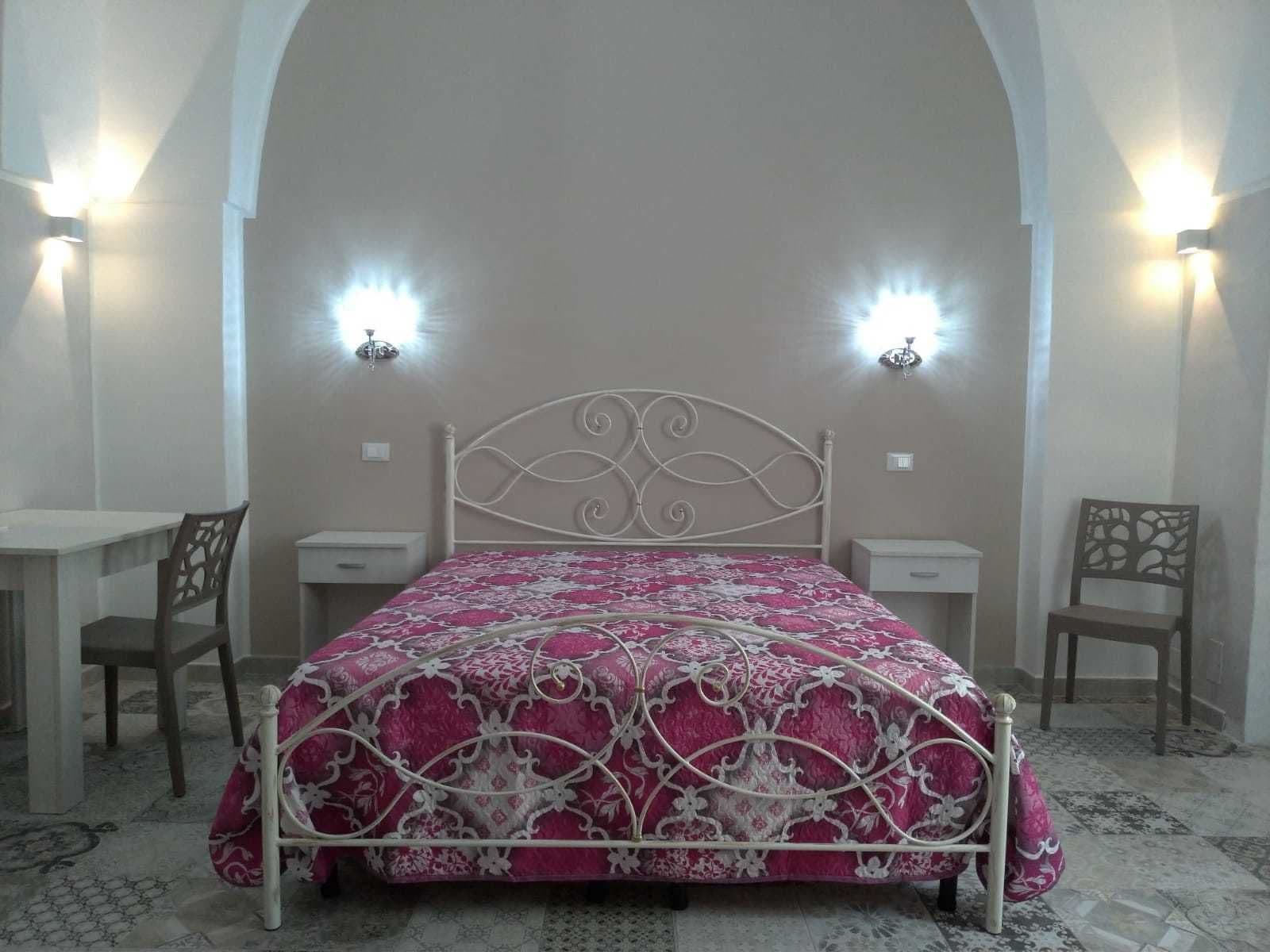 A bedroom with a bed, two nightstands, and two chairs.