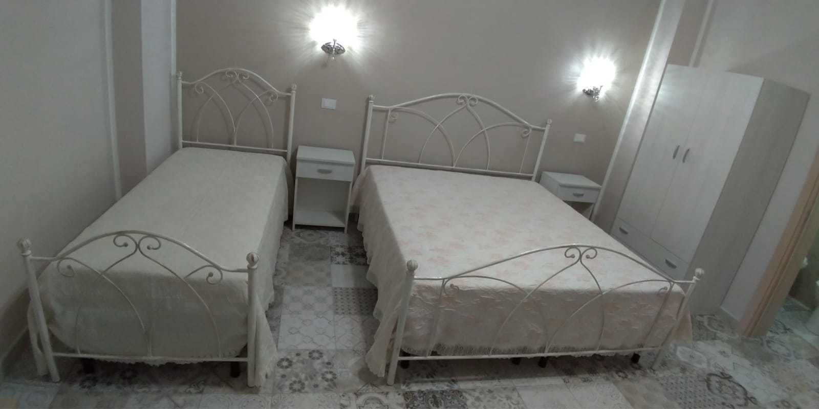 A bedroom with two single beds, a nightstand, a wardrobe, and a patterned floor.