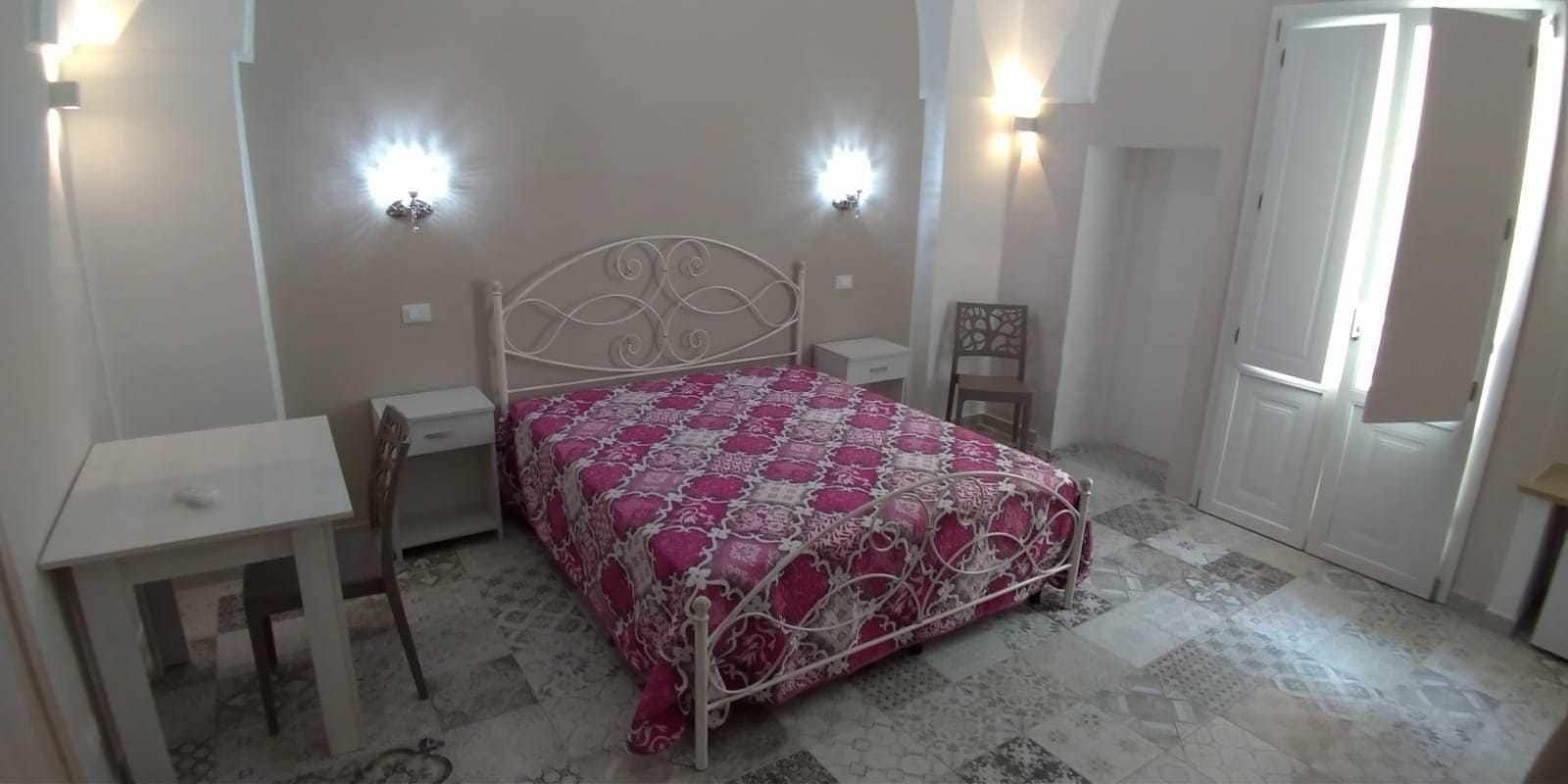Quarto com uma cama, uma escrivaninha, uma cadeira e duas luminárias.