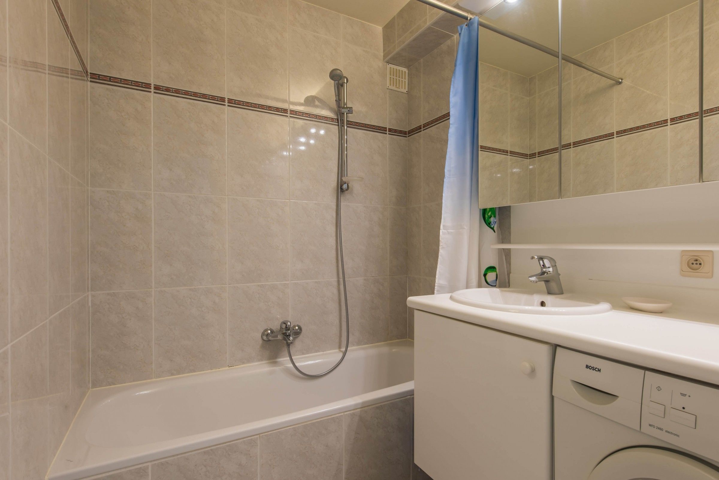 Ein Badezimmer mit Badewanne, Dusche, Waschbecken und einer Bosch Waschmaschine.