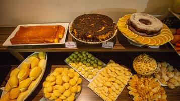 En buffet med forskellige spiser, heriblandt kager, wienerbrød og brød.