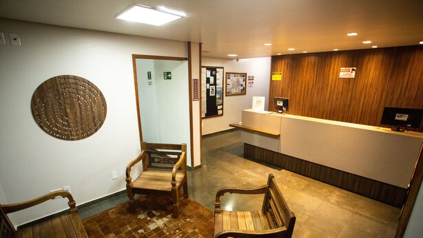 Una zona de recepción con un mostrador de madera, un tablón de anuncios y dos sillas de madera.