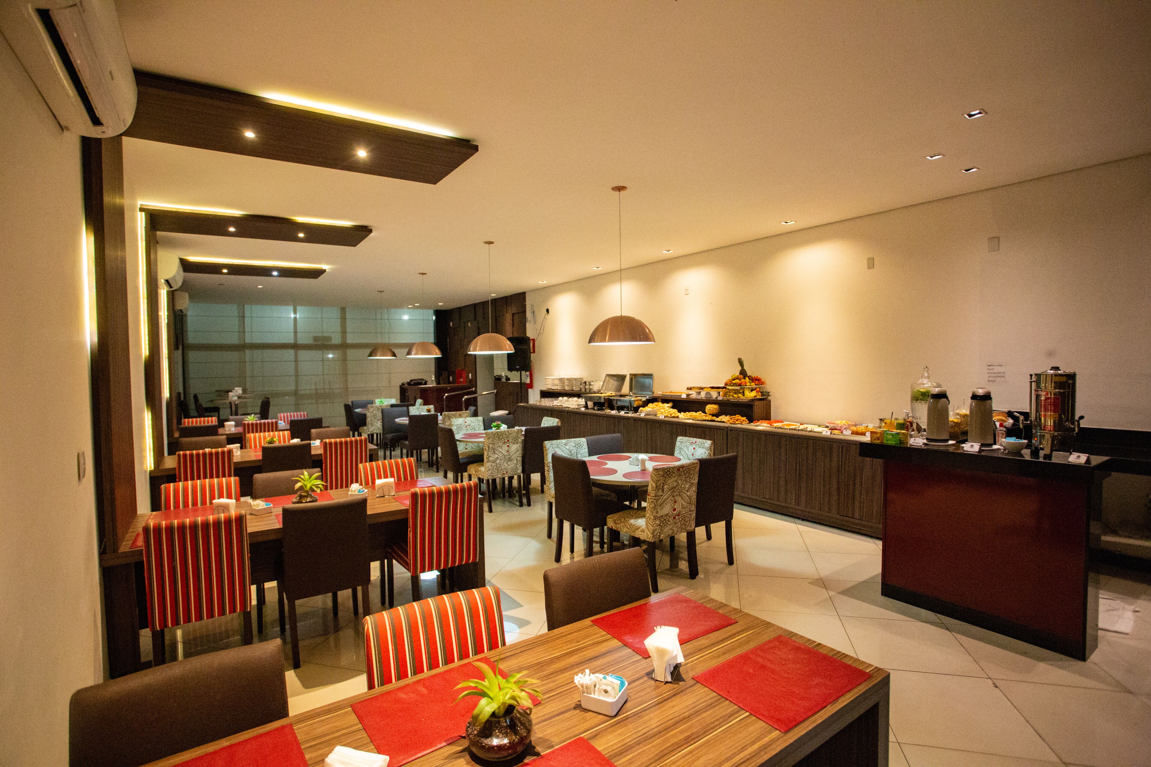 A modern restaurant with multiple dining tables and chairs, a kitchen area, and a bar counter.