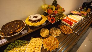Un bufé con diversos alimentos, entre ellos frutas, pasteles y postres.