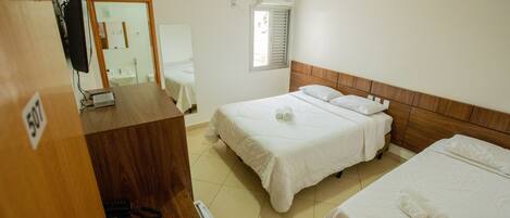 A hotel room with two beds, a desk with a computer, a mirror, and a window with blinds.