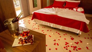 Habitación de hotel con cama, un balde de champán y un frutero sobre la mesa.