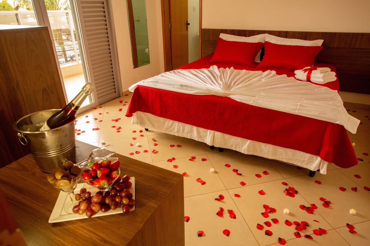 Habitación de hotel con cama, un balde de champán y un frutero sobre la mesa.