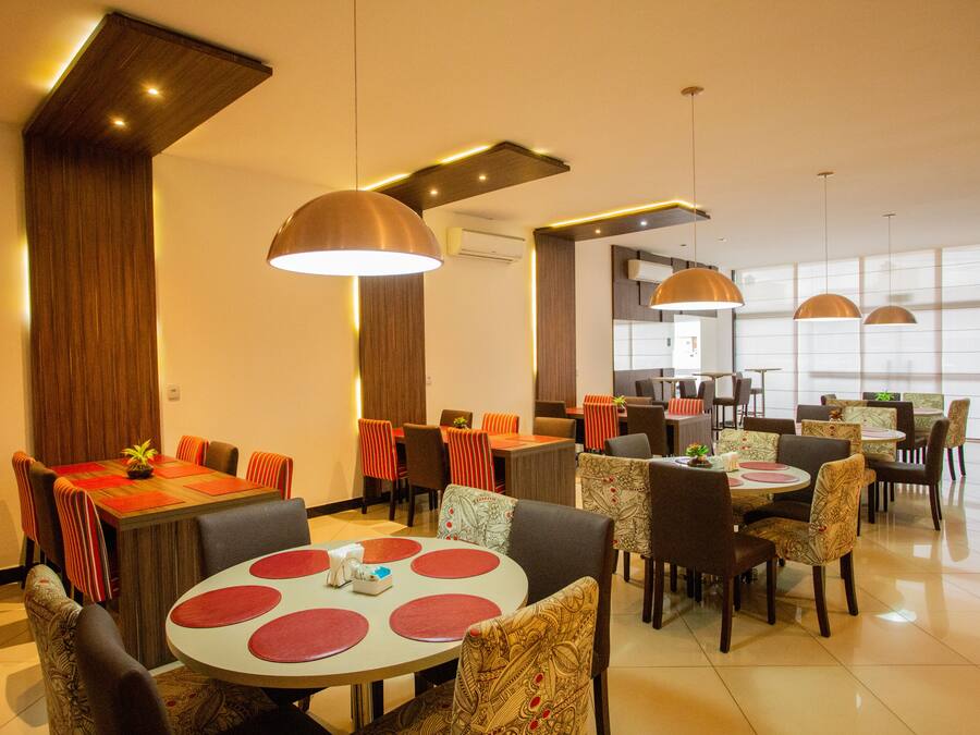 A modern dining area with multiple tables and chairs, wooden accents, and pendant lighting.