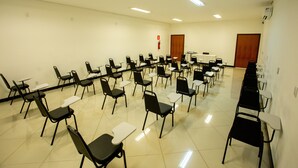 Un salón de conferencias con filas de sillas y mesas, un atril y un extintor en la pared.