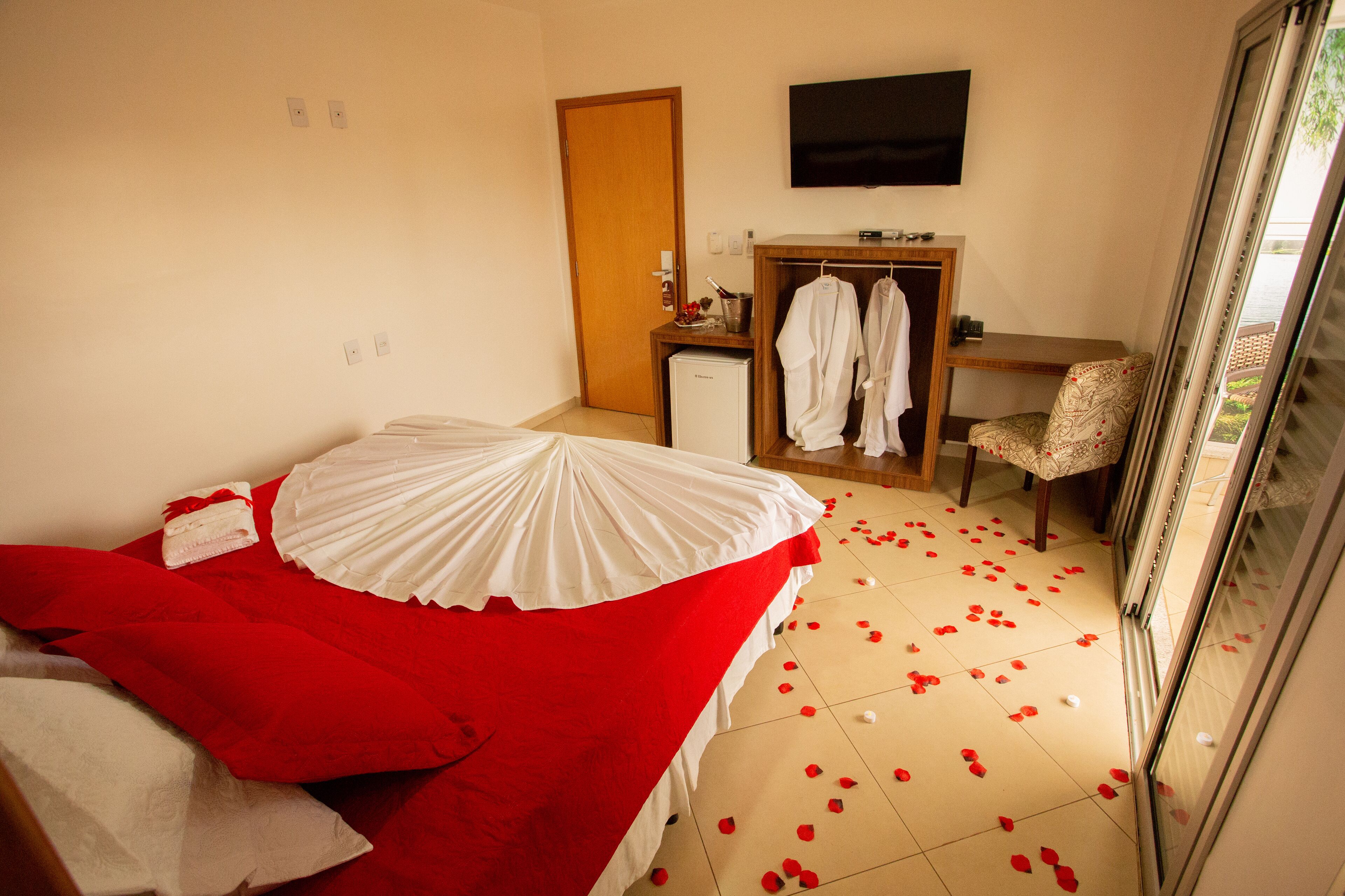 A hotel room with a bed, a desk, a chair, and a TV on the wall.