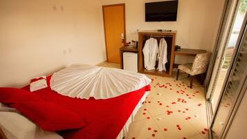 A hotel room with a bed, a desk, a chair, and a TV on the wall.