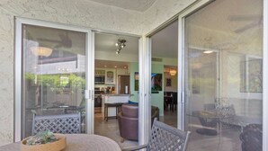 En patio med et rundt bord og stole, en glasdør ind til et køkken, og udsigt til indretningen indeni.