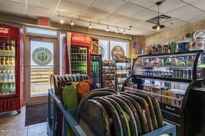 A convenience store interior with a Coca-Cola refrigerator, a freezer, and a display of snacks and drinks.
