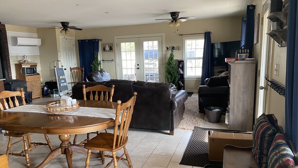 A spacious living room with a dining area, featuring a wooden dining table, chairs, a sofa, and a television. - Family Cabin with a large front porch - Close to playground and pond (Winslow)