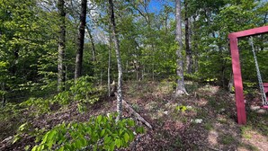 A forested area with a red wooden swing set.