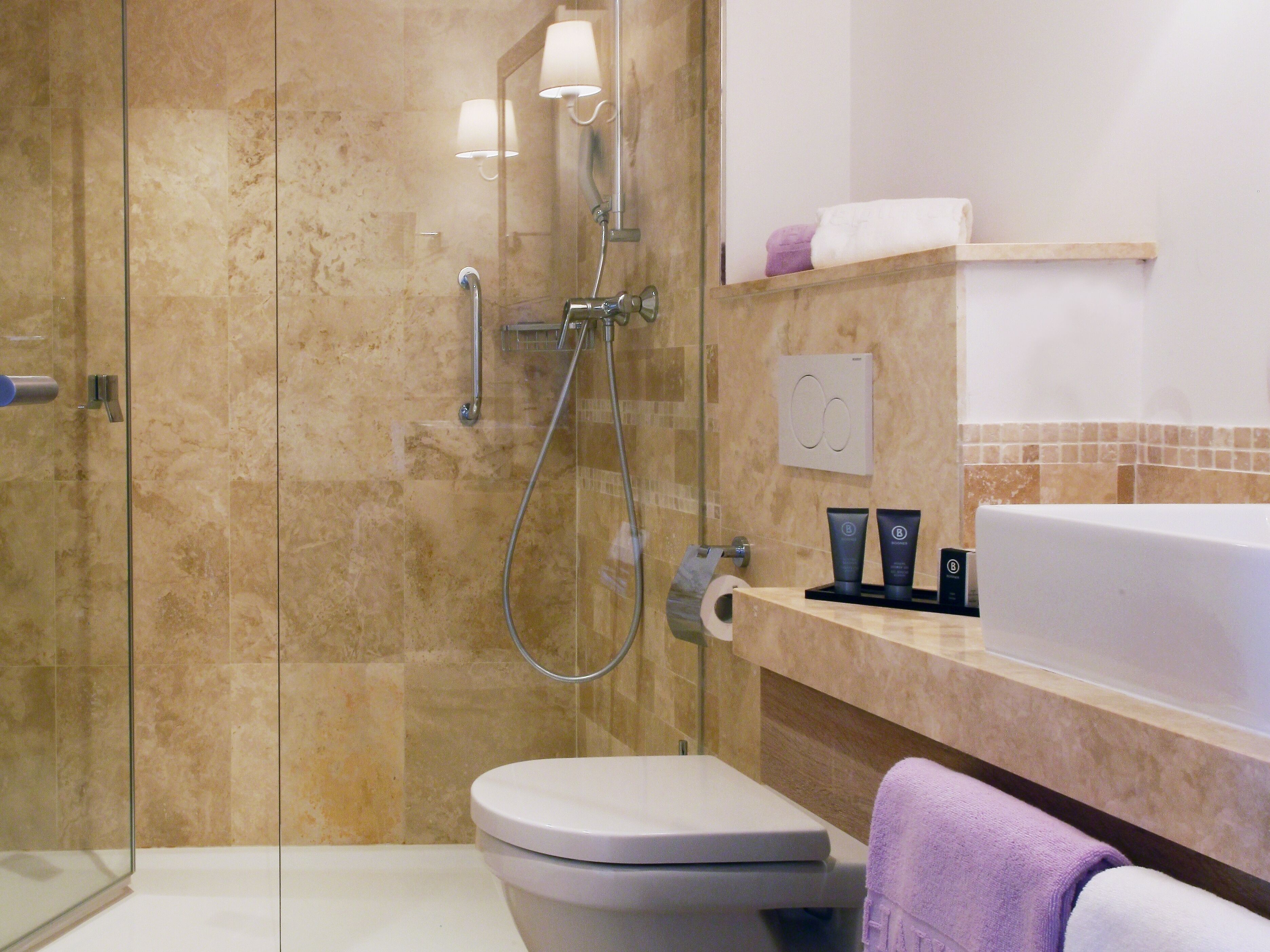 Une salle de bain moderne avec une douche à parois de verre, des toilettes blanches et un meuble-lavabo doté d’un évier et d’un porte-serviettes.