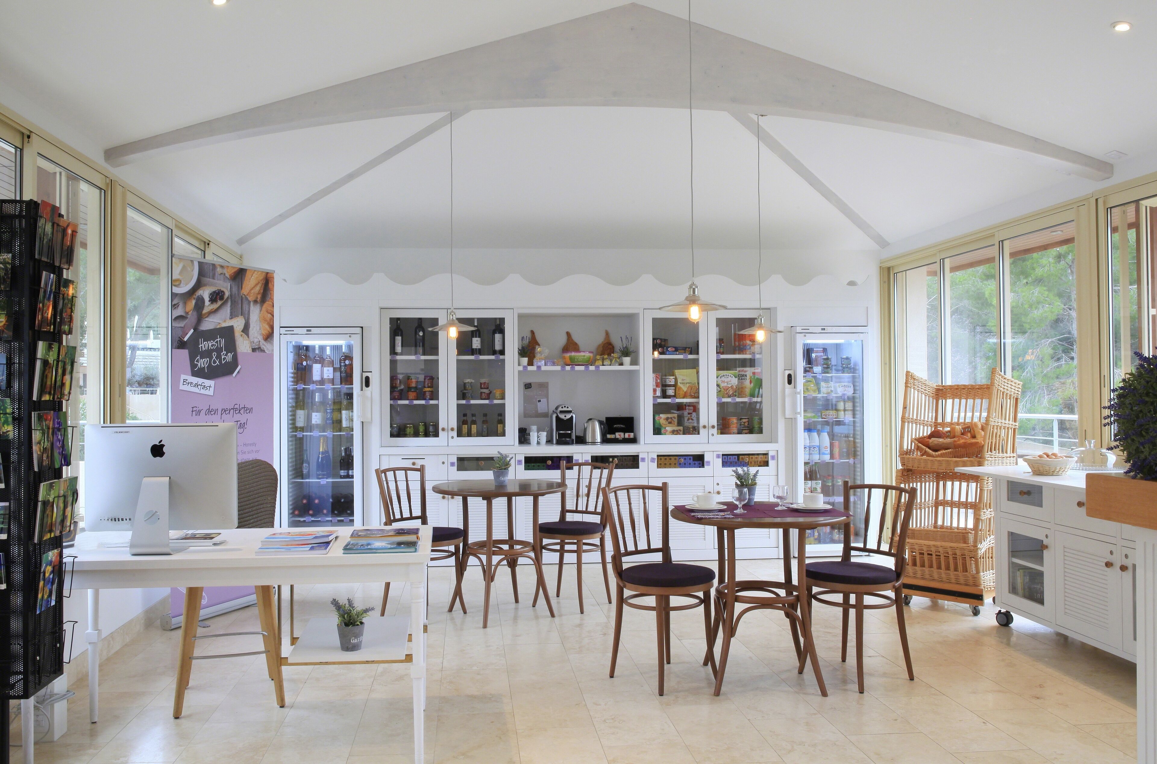 Een modern café met een witte inrichting, houten meubels en grote ramen.