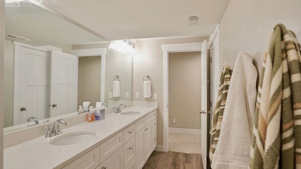 A bathroom with a double sink, a large mirror, and a towel rack. - Spacious Basement Apartment with separate entrance (Saratoga Springs)