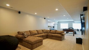 Una sala moderna con un sofá modular, un televisor de pantalla plana y una mesa de fútbol.