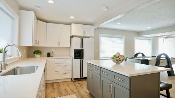 Una cocina moderna con armarios blancos, una isla central y un refrigerador empotrado.