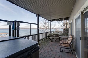 Enjoy al fresco dining with a view of the water from this outdoor space, featuring a grill, picnic table, and benches.