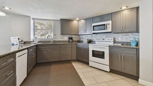 Una cocina moderna con gabinetes grises, microondas integrado, estufa y lavavajillas.