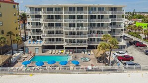 Un hotel de varios pisos con balcones, piscina y zonas de estar al aire libre.