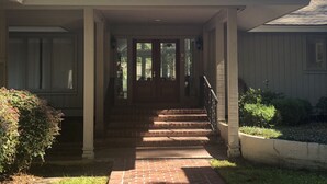 A house with a front porch, a brick pathway leading to the entrance, and a small garden area. - Sea Pines Home with Sparkling Heated Pool-Hole #2 Harbour Town Golf Links-Grill (Hilton Head Island)