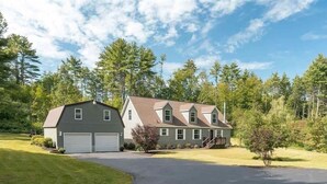 A two-story house with a garage, surrounded by a well-maintained lawn and trees. - 6BR Family Retreat - Heated Pool & Game Room - Near Lake George & Saratoga (Corinth)