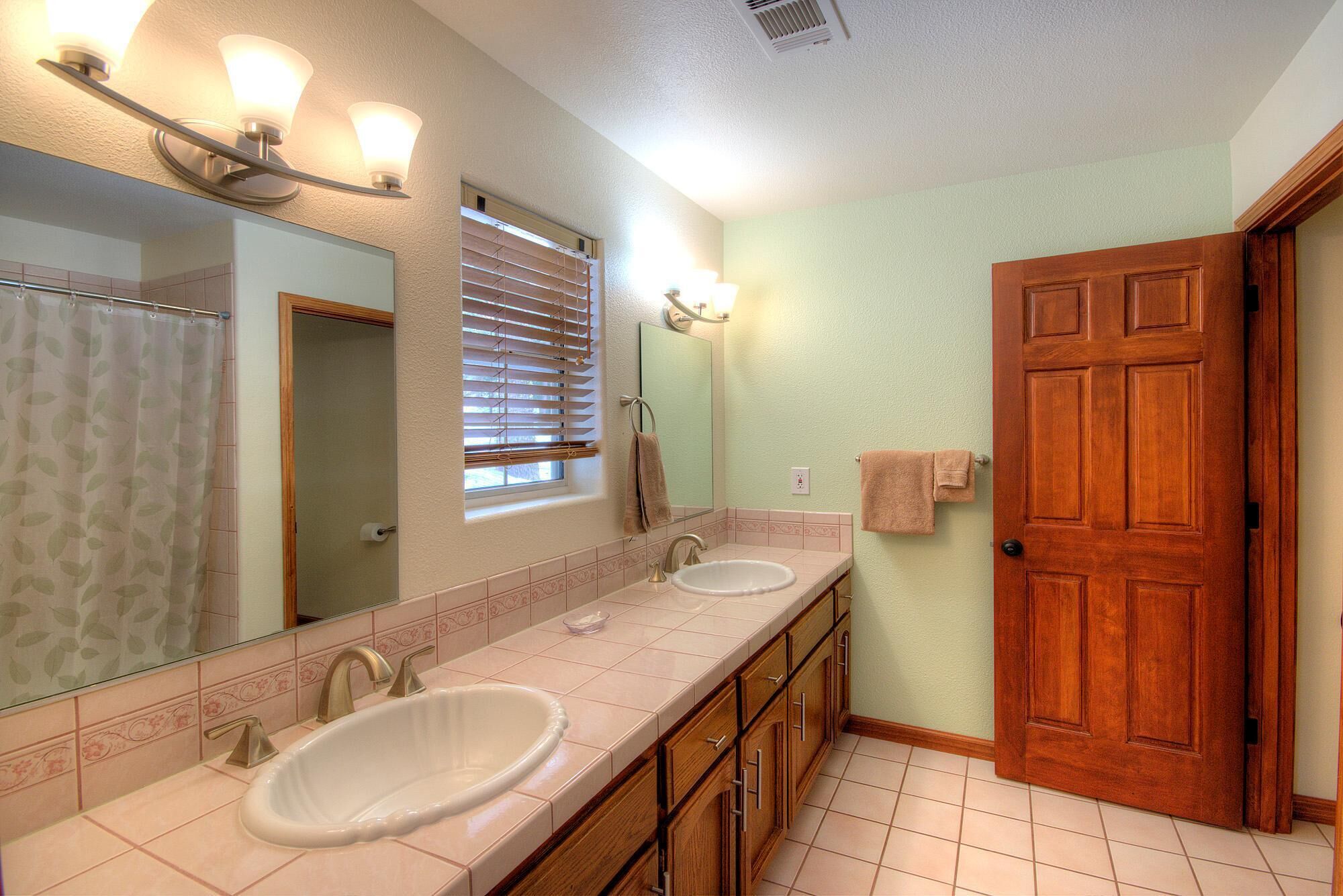 Une salle de bain avec deux lavabos, un miroir et une porte en bois.