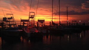Un port de plaisance au coucher du soleil, avec des bateaux amarrés et un ciel dégagé.