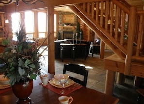 Cozy dining area with a stone fireplace, wooden staircase, and a dining table set for meals.