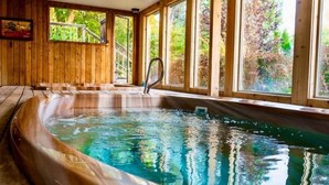 Una cabaña de madera con jacuzzi y ventanas amplias.