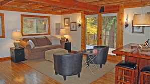 A cozy living room with a wooden ceiling, a sofa, two armchairs, a coffee table, and a dining area with a table and chairs. - Peaceful, Private Cabin overlooking the Clearwater River. Dbl occ rates (Orofino)
